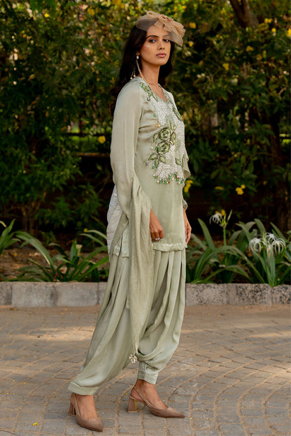 Box pleat pants and an embroidered vest are paired with a long cape