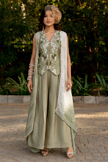 Box pleat pants and an embroidered vest are paired with a long cape